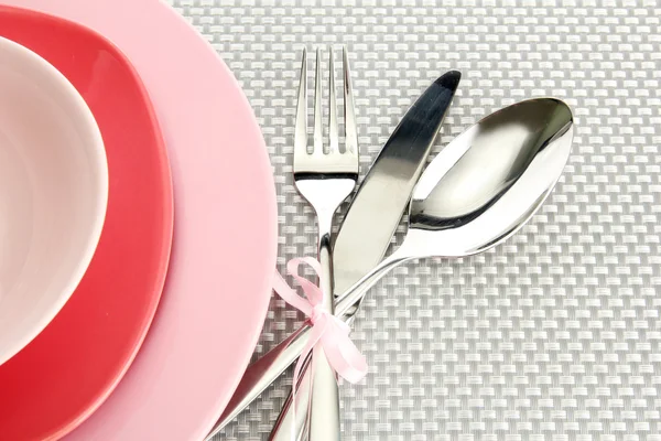 Pink empty plates with fork, spoon and knife on a grey tablecloth — Stock Photo, Image