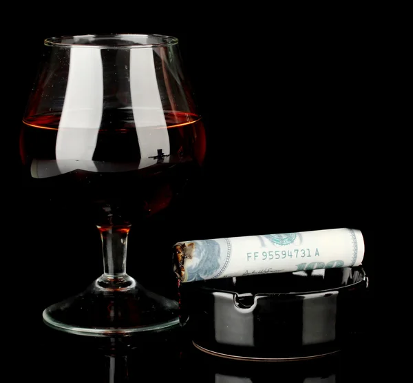 Cigar of the 100 dollar bill and an ashtray and glass of brandy isolated on — Stock Photo, Image
