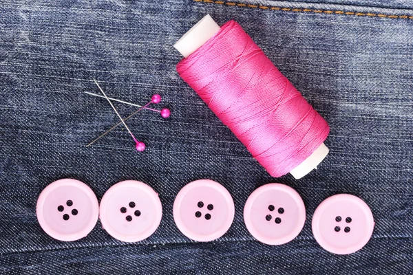 Colorful sewing buttons with thread on jeans closeup — Stock Photo, Image