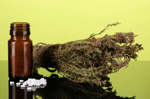 Пляшка з таблетками і травами на зеленому фоні. концепція гомеопатії — стокове фото