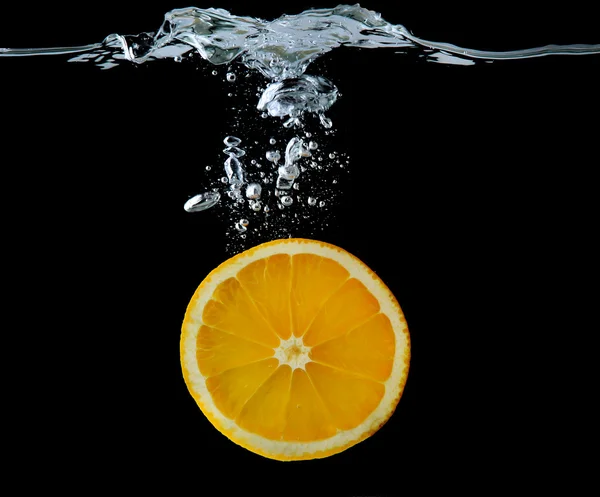 Rebanada de naranja en el agua sobre fondo negro —  Fotos de Stock