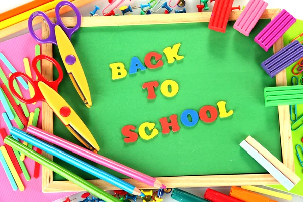 Kleine Kreidetafel mit Schulmaterial auf weißem Hintergrund. Zurück zur Schule — Stockfoto