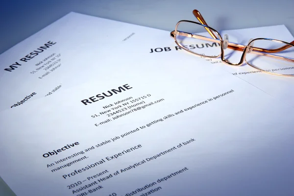 Primer plano del curriculum vitae con gafas sobre fondo azul —  Fotos de Stock