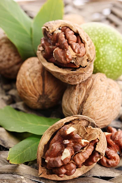 Nueces con hojas verdes, sobre fondo de mimbre — Foto de Stock