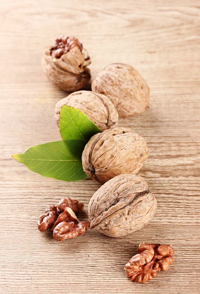 Vlašské ořechy se zelenými listy, na dřevěné pozadí — Stock fotografie