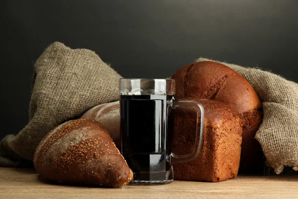 Tankard of kvass and rye breads, on wooden table on grey background — Stock Photo, Image