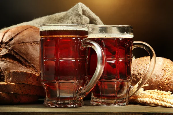 Tanques de pães de kvass e centeio com orelhas, na mesa de madeira em backgr marrom — Fotografia de Stock