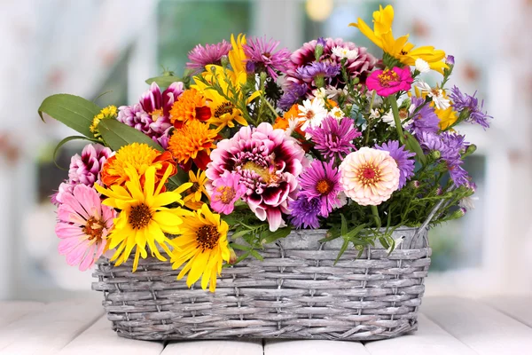 Mooi boeket van heldere bloemen in mand op houten tafel — Stockfoto