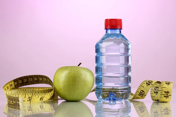 Fles water, apple en meetband op paarse achtergrond — Stockfoto