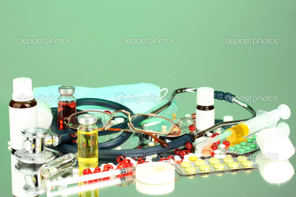 medicines and a stethoscope on a green background close-up