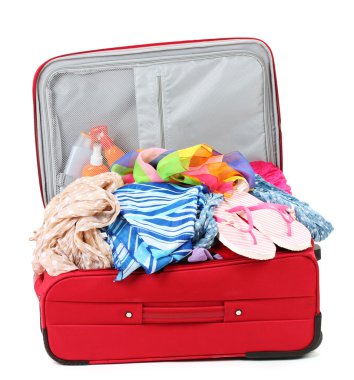 Suitcase with summer clothes, a hat and suntan isolated on white