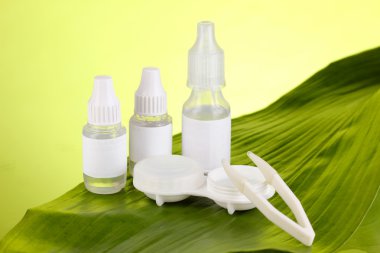 Göz damlaları ve yaprak yeşil zemin üzerine lensler