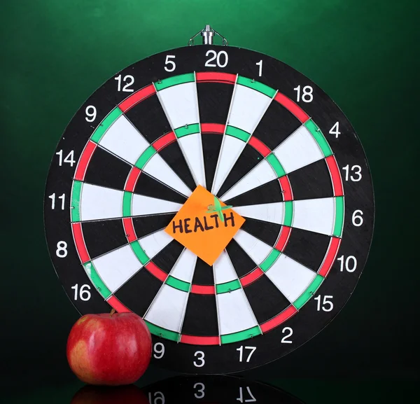 Darts with a sticker symbolizing health on colorful background — Stock Photo, Image