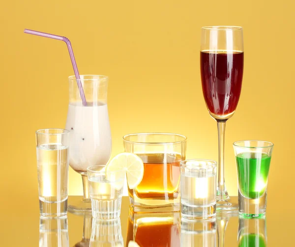 A variety of alcoholic drinks on yellow background — Stock Photo, Image