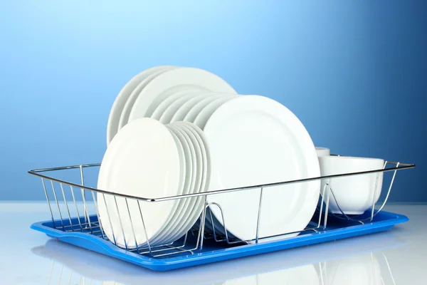 Чистий посуд на підставці на синьому фоні — стокове фото