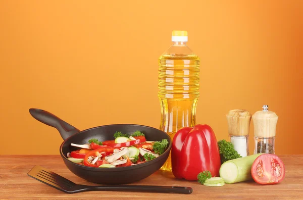 Frying pan with vegetables on red background — Stock Photo, Image