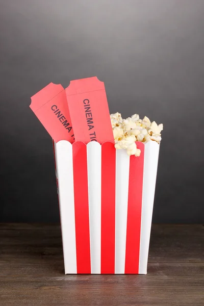 Popcorn med biljetter på träbord på grå bakgrund — Stockfoto