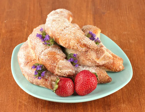 Panecillos frescos con fresa en el plato sobre fondo de madera — Foto de Stock