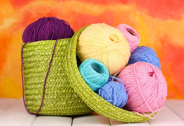 Colorful yarn for knitting in green basket on white wooden table on colorfu — Stock Photo, Image