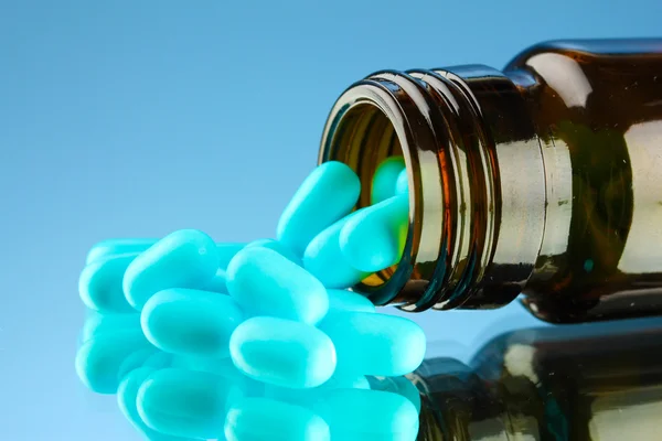 Pastillas en botella, sobre fondo azul —  Fotos de Stock