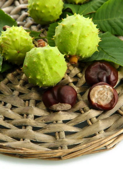 Chestnuts with leaves on wicker background — Stock Photo, Image