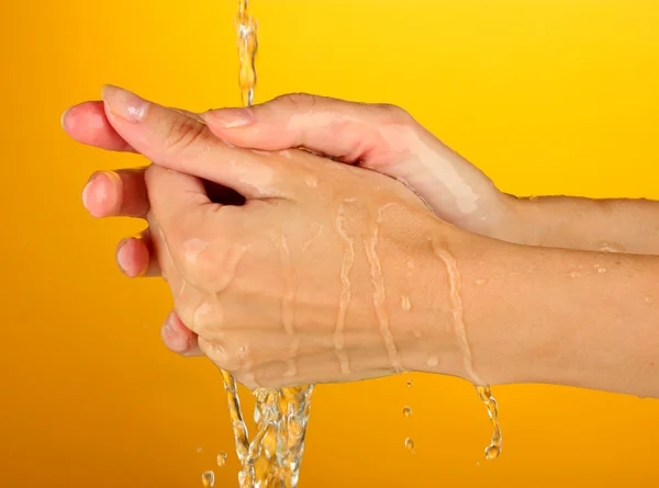 Wassen handen op oranje achtergrond close-up — Stockfoto