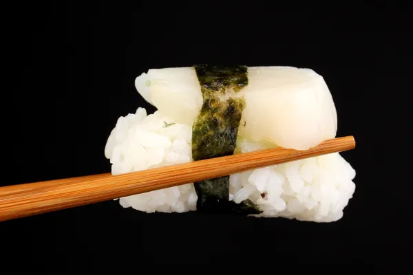 Tenendo sushi con bacchette isolate su nero — Foto Stock