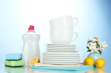 boş temiz tabak ve bardaklar bulaşık deterjanı, süngerler ve mavi zemin üzerine limon