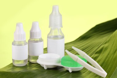 Göz damlaları ve yaprak yeşil zemin üzerine lensler