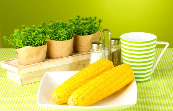 Gekookte maïs en bloemen op een groene achtergrond — Stockfoto