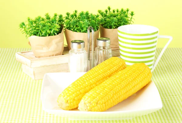 Gekookte maïs en bloemen op een groene achtergrond — Stockfoto