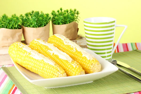 Boiled corn with butter on a green background — Stock Photo, Image