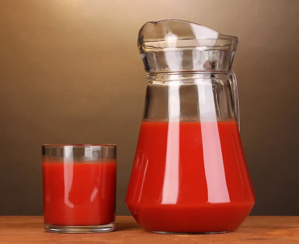 Tomatensaft in Krug und Glas auf Holztisch auf braunem Hintergrund — Stockfoto