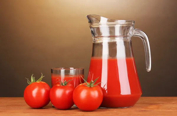 Tomatensap in werper en glas op houten tafel op bruine achtergrond — Stockfoto