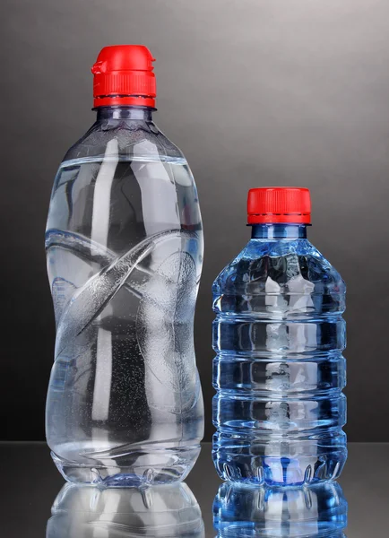 Plastové lahve s vodou na šedém pozadí — Stock fotografie