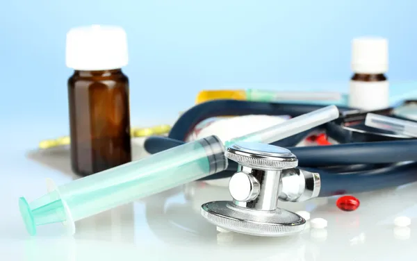 Medicines and a stethoscope on a blue background close-up — Stock Photo, Image