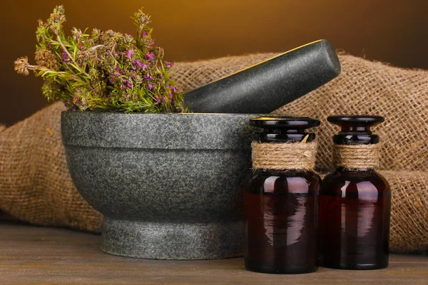 Thyme herb and mortar on wooden table on brown background — Stock Photo, Image