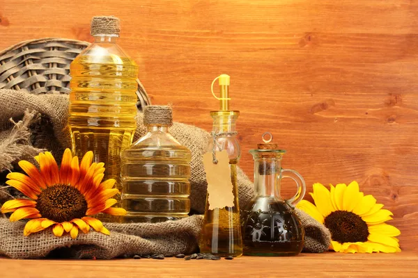 Aceite en botellas, girasoles y semillas, sobre fondo de madera —  Fotos de Stock