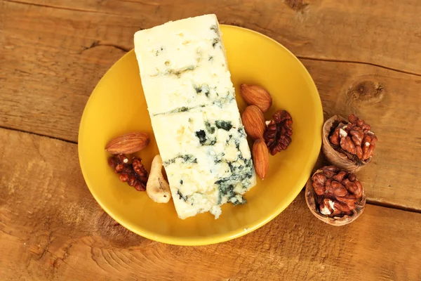 Сыр с плесенью и грецкими орехами на тарелке на деревянном фоне крупным планом — стоковое фото