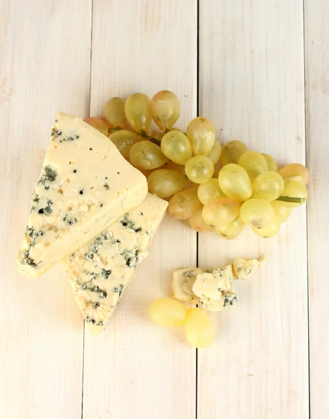 Сир з цвіллю і виноградом на білому дерев'яному фоні крупним планом — стокове фото
