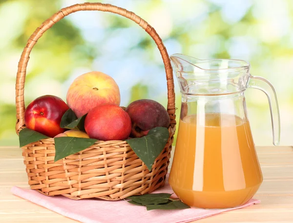 Mogna persikor i korg och juice på träbord på naturliga bakgrund — Stockfoto