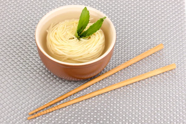 Tagliatelle asiatiche in ciotola su tappetino grigio — Foto Stock