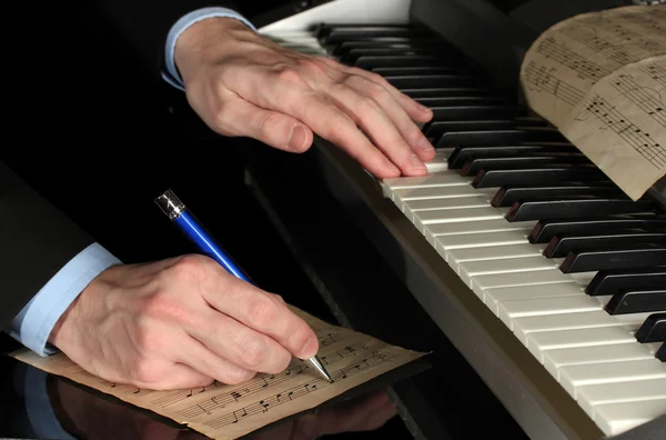 Man handen speelt piano en schrijft op dunschiller voor notities — Stockfoto