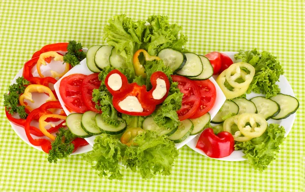 Нарезанные овощи и соус на тарелке на зеленой скатерти — стоковое фото