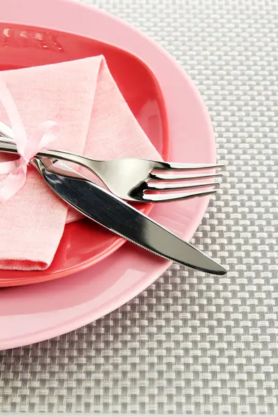 Placas vazias rosa com garfo e faca em uma toalha de mesa cinza — Fotografia de Stock