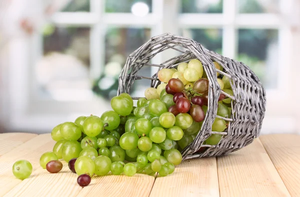 Uvas verdes maduras em cesta na mesa de madeira no fundo da janela — Fotografia de Stock