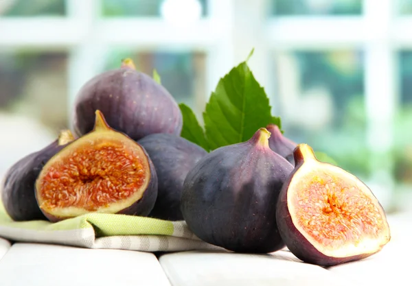 Ripe sweet figs with leaves, on wooden table, on window background — Stock Photo, Image