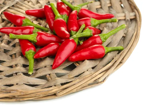 Little hot peppers on wicker mat isolated on white — Stock Photo, Image