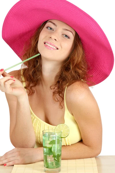 Sorridente bella ragazza seduta a tavola con cappello da spiaggia e cocktail iso — Foto Stock