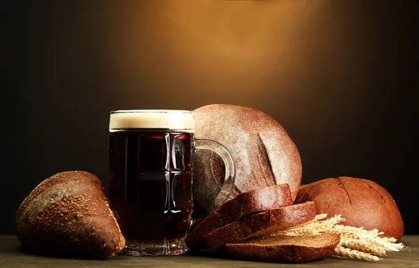 Tankard de kvass e pão de centeio com orelhas, em mesa de madeira em backgro marrom — Fotografia de Stock